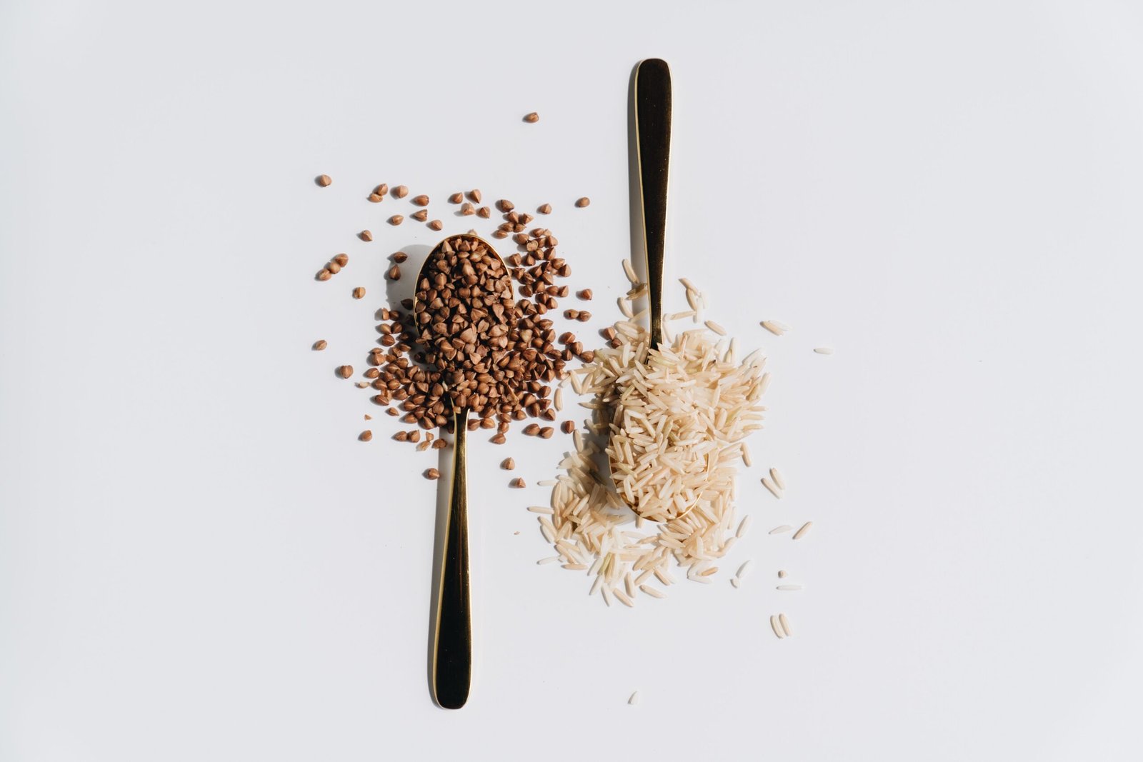 Artistic flat lay of grains with spoons on a white background. Perfect for culinary themes.